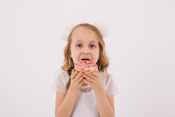 Funny little girl eating a donut on a white background