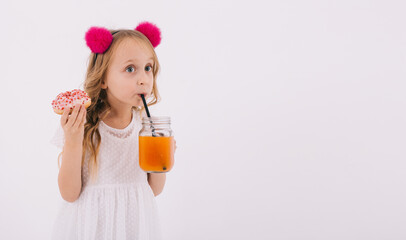 Funny blonde girl eating a donut and drinking fruit juice on a white background