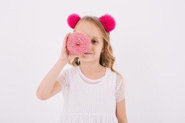 Funny little girl eating a donut on a white background