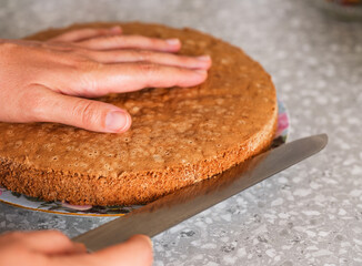 A woman cutting a homemade gluten free sponge cake with a knife