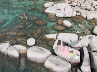 Lake Tahoe rocky shoreline. Ladies relaxing in the crystal clear water