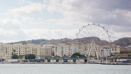 Frachthafen in Malaga mit Frachtschuppen und Riesenrad auf der rechten Seite