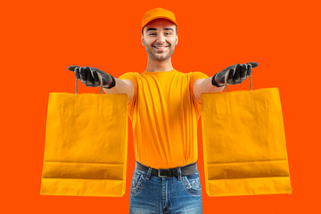 Delivery man with yellow paper bags. Courier in uniform cap and t-shirt, gloves service fast delivering orders. Young guy holding a bag package. Character on isolated background for mockup design