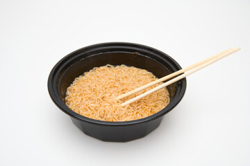 noodles in black takeout bowl with chopsticks isolated on white 