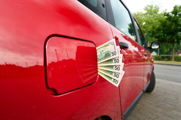 Naklejka premium Fifty dollar notes sticking out of a car's closed fuel tank