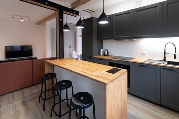 Dark gray kitchen furniture in a modern kitchen with a counter and bar tables