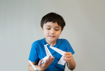 Happy school boy looking at origami Swan paper on his hands. Kid learning paper art origami lesson,...