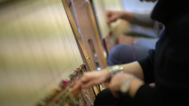 close-up video of a woman weaving a rug in slow motion