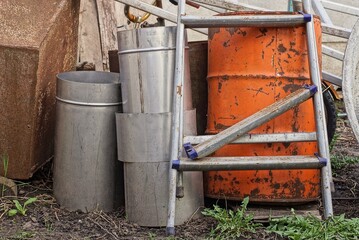 a pile of garbage from a broken gray metal stepladder with a red barrel and pieces of iron on the...