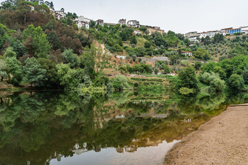 Fototapeta na wymiar Sand next the river Mondego with mirror effect of trees on the bank and the hill, Penacova PORTUGAL