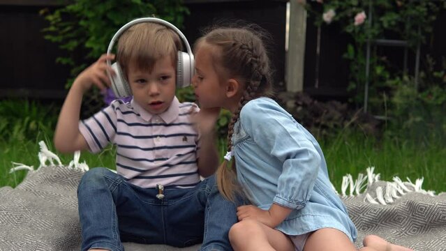 Two naughty Siblings dont share. boy ans girl listening to music on headphones outside. Children and technology. Brother Sister. Love of music, dreams hobbies. Childhood, musicality, hobby. Friendship