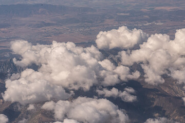 Aerial view above clouds looking down at canyons and foot hills in the southwestern USA