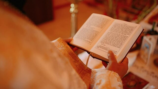 Close up of priest reading holy bible with rosary. View from back shoulders. Pope man reading from holy bible, close up. Priest during a wedding ceremony nuptial mass (shallow DOF color toned image