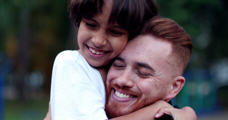 Dad and son embrace huggging each other outside, white father and mixed race child