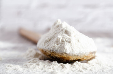 A spoonful of white flour on wooden backdrop. Close-up.