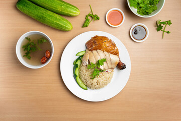 Steamed and Roasted Chicken Rice with raw cucumber, Coriander, salad, sauce and soup served in a dish isolated on wooden background top view