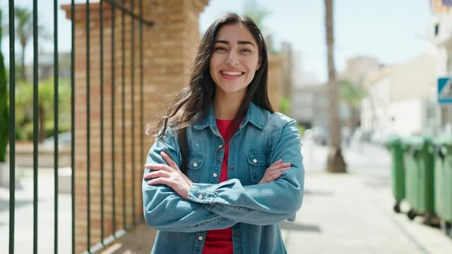 Young hispanic girl smiling confident standing with arms crossed gesture at street