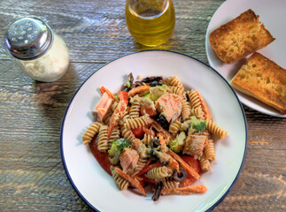 Top view of salmon pasta salad on natural wood surface