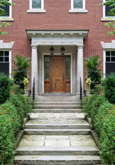 Fototapeta na wymiar Long flagstone path leading to portico entrance of traditional brick house, with elegant wood grain front door with sidelights