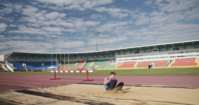 Sportsman practicing long jump on arena