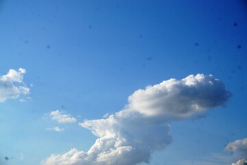 Weißes Wolkengebilde am blauen Himmel bei Sonne am Abend im Sommer