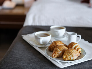 breakfast with coffee and croissant in hotel room