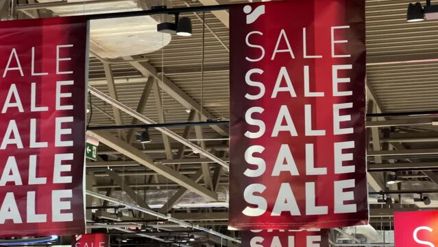 Large banners with the word "Sale" hanging from the ceiling in a shopping mall