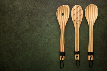 Cooking bamboo spoons on dark green background, top view