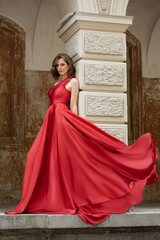 Beautiful fashionista in a red flowing long dress. City walks