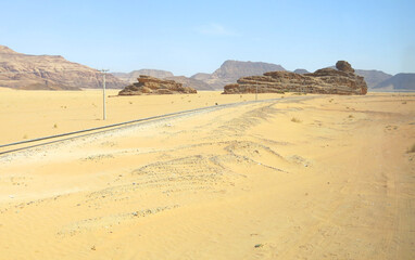 Fototapeta na wymiar railroad tracks without train in the middle of the desert sand and some rocks