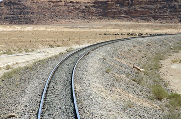 Curve of the railway tracks without train in the middle of the desert sand