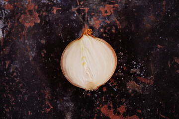 A halved onion on a black metal surface background.