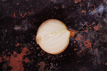 A halved onion on a black metal surface background.