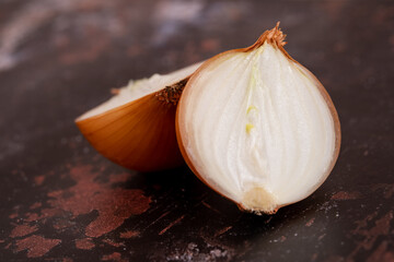 A halved onion on a black metal surface background.