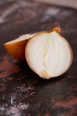 A halved onion on a black metal surface background.