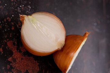 A halved onion on a black metal surface background.