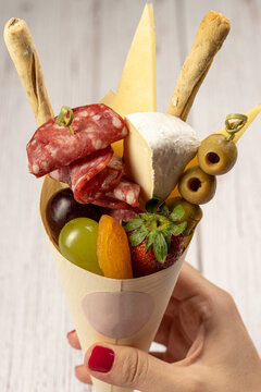charcuterie cone with cheeses, crackers, strawberries, olives, kiwi, grapes, pastrami, salami, apricot and walnuts