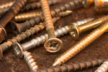 Screws on rusty textured metal surface close-up. Warm red orange brown color scheme. Industrial background.