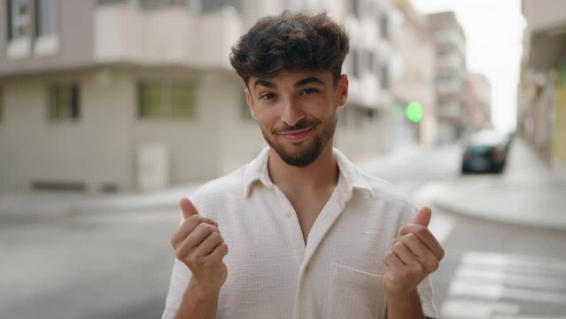 Young arab man smiling confident doing spend money gesture at street