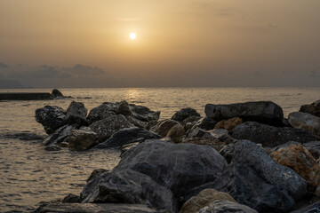 Sonnenuntergang am Meer in Italien. Vielfalt der Farben und Farben der aufgehenden Sonne. Meereslandschaft mit Wasser und Steinen.