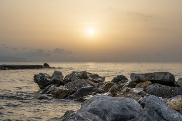 Sonnenuntergang am Meer in Italien. Vielfalt der Farben und Farben der aufgehenden Sonne. Meereslandschaft mit Wasser und Steinen.
