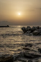 Fotobehang Sonnenuntergang am Meer in Italien. Vielfalt der Farben und Farben der aufgehenden Sonne. Meereslandschaft mit Wasser und Steinen. © CreativeImage