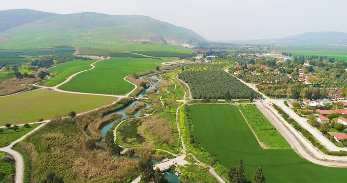 Aerial view of cultivated fields with hills in the background and Kibbutzim Stream, Nir David, Northern District, Israel.
