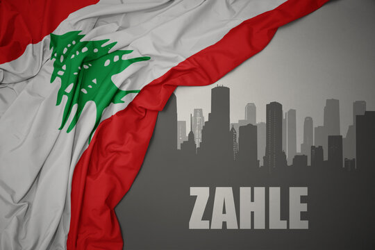 abstract silhouette of the city with text Zahle near waving national flag of laos on a gray background.