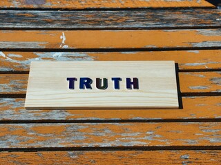 TRUTH in rainbow lettering on rustic orange wood background