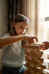a girl of 5-6 years old plays in the room in indushki, a child builds a tower of wooden sticks, a girl plays a construction set, educational toys for home and kindergarten