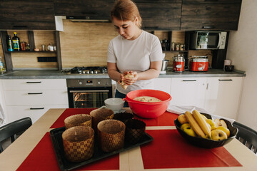 young mother kneads the dough for baking festive Easter cakes