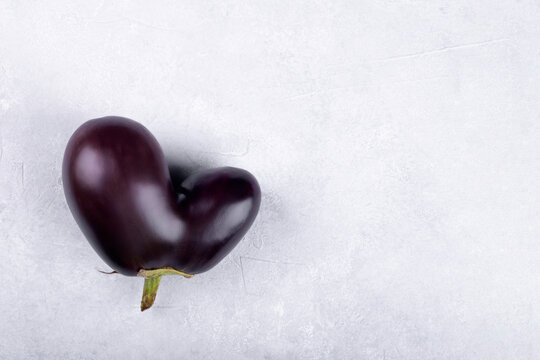 Heart Shaped Ugly Eggplant Isolated On Concrete Grey Background, Funny Aubergine Vegetables For A Healthy Diet With Copy Space, Funny Unnormal Vegetable Concept