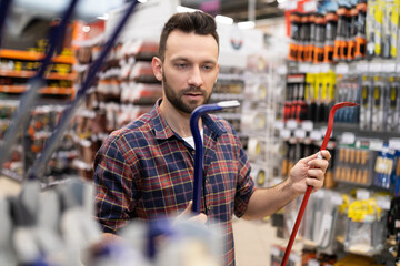 a young man in a hardware store chooses a nail puller