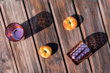 two magenta colored glasses and two peaches on wooden boards on a sunny summer day. Flat lay. Minimal concept for summer leisure or relaxed holidays banner. Copy space.